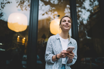 Glad woman looking away while surfing on phone