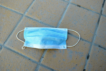 abandoned used medical mask on the sidewalk empty street