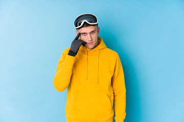 Young skier man pointing temple with finger, thinking, focused on a task.