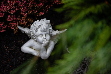 Figur von nachdenklichem Engelchen auf Grab