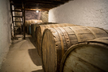 Wine cask barrels in cellar lined up against wall