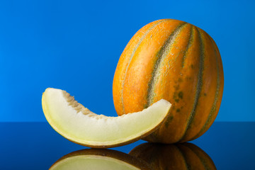 pop art. Melon and a slice of melon with reflection on a blue background. Free space for text.