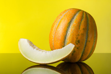 pop art. Melon and a slice of melon with reflection on a yellow background. Free space for text.