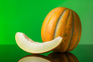 pop art. Melon and a slice of melon with reflection on a green background. Free space for text.