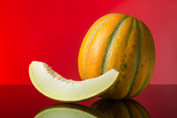 pop art. Melon and a slice of melon with reflection on a red background. Free space for text. close-up shot.