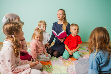 Children sitting on the floor and listen teacher