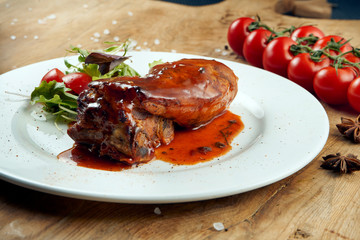 Appetizing baked pork ribs in honey and mustard sauce on a wooden background. Beer snack or side dish. Close up view on tasty barbecue food