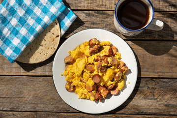 Scrambled eggs with sausage breakfast on wooden background