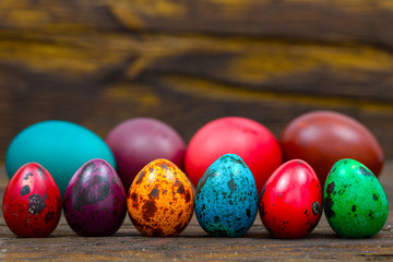 painted eggs of different colors on a wooden table, Easter decoration, Place for text