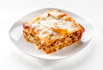 lasagna piece plate with minced meat and melted cheese close-up on white background - obrazy, fototapety, plakaty