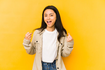 Young chinese woman isolated on a yellow background cheering carefree and excited. Victory concept.