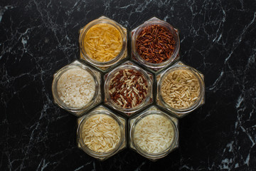Collection of gourmet rice in glass jars - brown rice, red rice, black rice.