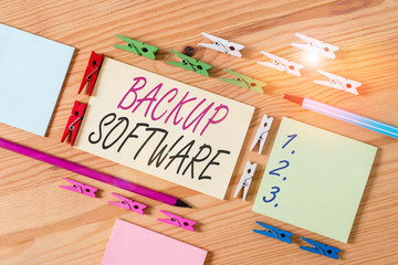 Word writing text Backup Software. Business photo showcasing create extra exact copies of files or entire computers Colored clothespin papers empty reminder wooden floor background office
