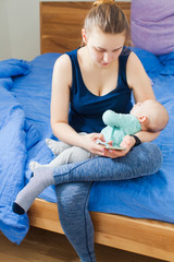 Fototapeta premium Mother using mobile phone while sitting with baby