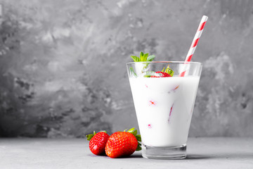 Glass of milkshake with strawberries and mint on a concrete surface. Kefir cocktail with...