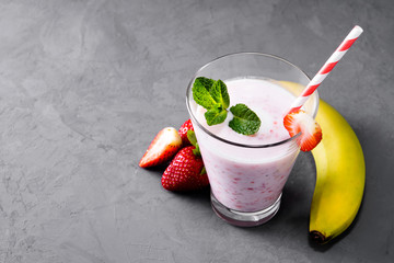 Glass of milkshake with strawberries and mint on a concrete surface. Kefir cocktail with strawberries and banana. close-up. Strawberry protein cocktail on a gray concrete background.