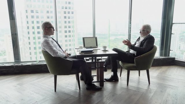 Two senior businessman planning target finance from statistic graph on laptop computer in the office, manager meeting and discussion and analysis from information chart of sales for marketing.