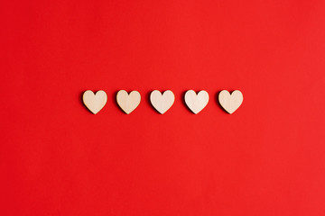 Five wooden hearts on a red background.