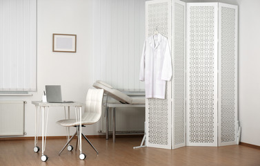 Doctor's office interior with desk, examination couch and folding screen