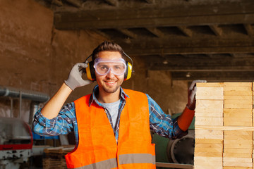 Handsome worker in a professional uniform working at wood shop