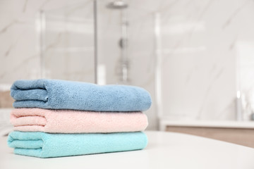 Stack of color towels on white table in bathroom, closeup. Space for text