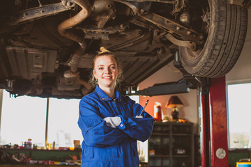 Confident smiling auto mechanic woman in overalls