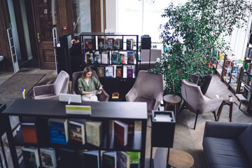 Young female relaxing in armchair in bookstore