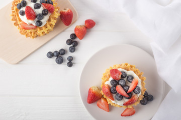 Delicious waffles with fresh fruit and berries on a white wooden table. Waffles with strawberries...