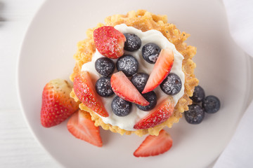 Delicious waffles with fresh fruit and berries on a white wooden table. Waffles with strawberries and blueberries. Free space for text. Traditional belgian waffles with fresh fruit. Stack of waffles w