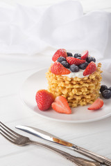 Delicious waffles with fresh fruit and berries on a white wooden table. Waffles with strawberries and blueberries. Free space for text. Traditional belgian waffles with fresh fruit. Stack of waffles w