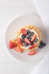 Delicious waffles with fresh fruit and berries on a white wooden table. Waffles with strawberries and blueberries. Free space for text. Traditional belgian waffles with fresh fruit. Stack of waffles w