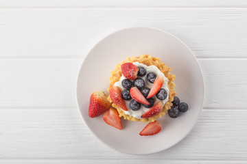 Delicious waffles with fresh fruit and berries on a white wooden table. Waffles with strawberries...