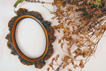 Empty vintage round picture frame and dried flowers. 