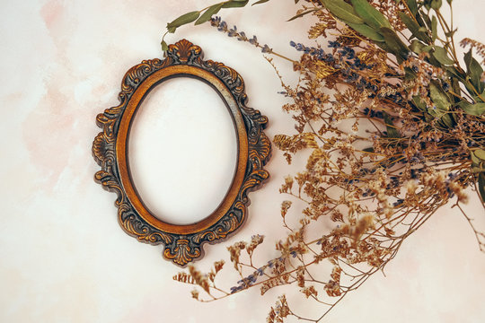 Decorative bronze vintage oval photo frame and dried flowers. 