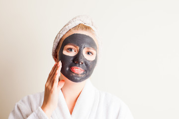 Young beautiful woman in a mask for the face of the therapeutic black mud