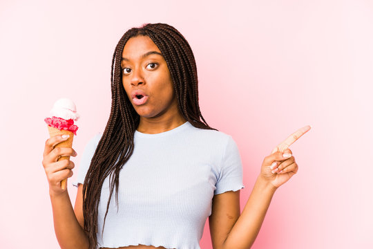 Young african american woman holding an ice cream isolated pointing to the side
