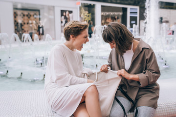 Two girls have fun in the mall, a fountain in the background