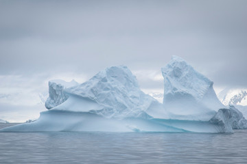 Antarctic icebergs and majestic landscape, cloudy blue sky