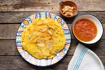 Spanish scrambled eggs with potatoes called tortilla or tapa on wooden background