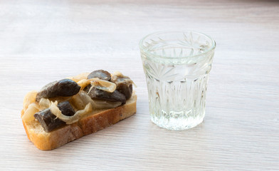 sandwich with fried mushrooms and onions. glass of vodka. on wooden background.