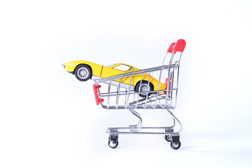 Concept of buying a new car. Toy car in shopping basket isolated on white background