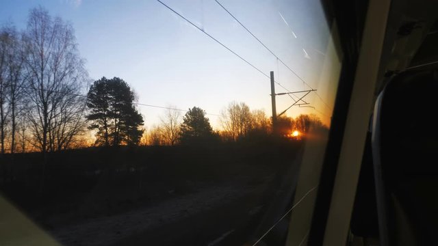 Beautiful view of sunset sky between trees from moving train window, thoughtful mood and nostalgia concept slow motion.