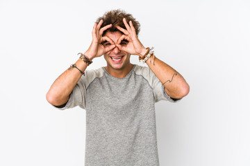 Young caucasian man against a white background isolated showing okay sign over eyes