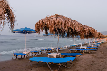 Sunset on the sea, deserted beach, with umbrellas and sun beds