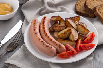 Close-up shot of fried potatoes with sausages and egg. Breakfast. Potatoes with sausages fried in oil, in rustic style. Frying pan with tasty cooked egg and sausages on table