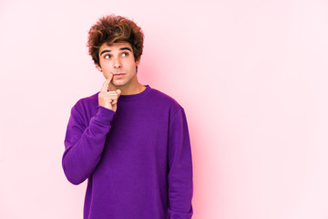 Young caucasian man against a pink background isolated looking sideways with doubtful and skeptical expression.