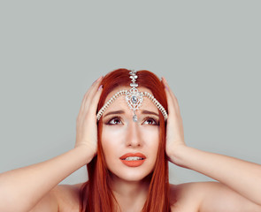 Stressed angry woman has temper tantrum, hand on head looking up tikka oriental jewelry on head. Isolated gray background.