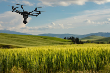 Fototapeta na wymiar A flying drone with camera with blured hills of Tuscany in the background