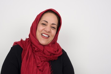 Horizontal portrait of pleasant-looking muslim female wearing hijab covering her face with hair looking happily to the camera.