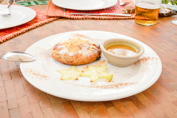 Moroccan chicken bisteeya, traditional Berber meat pie with almond, cinnamon and sugar, also known as bastilla and bsteeya, decorated with fuit and sauce in a white dish with spoon